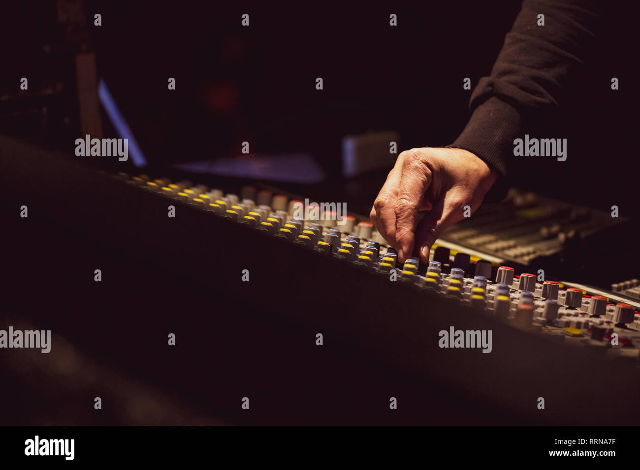 Mano di un ingegnere del suono mentre si lavora con il mixer e regola i livelli audio Foto Stock