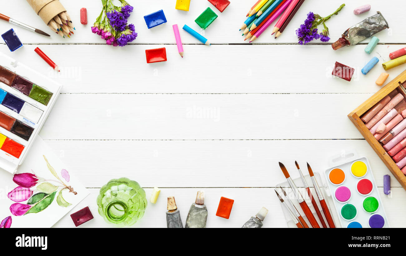 Vernici ad acquerello, pennelli per pittura, matite, il pastello su tavola bianco. Vista dall'alto. Lay piatto. Foto Stock