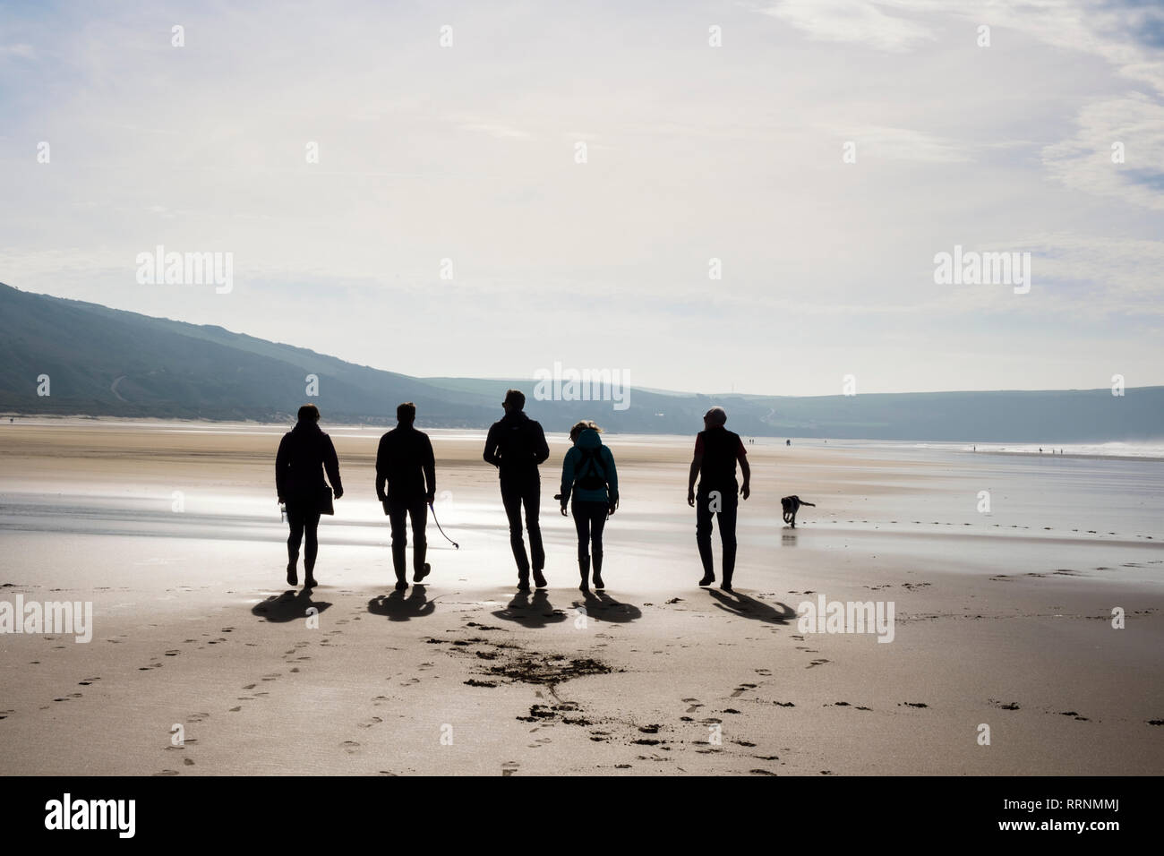 Un gruppo di persone che camminano su una tranquilla spiaggia di sabbia con la bassa marea. Woolacombe, North Devon, Inghilterra, Regno Unito, Gran Bretagna Foto Stock