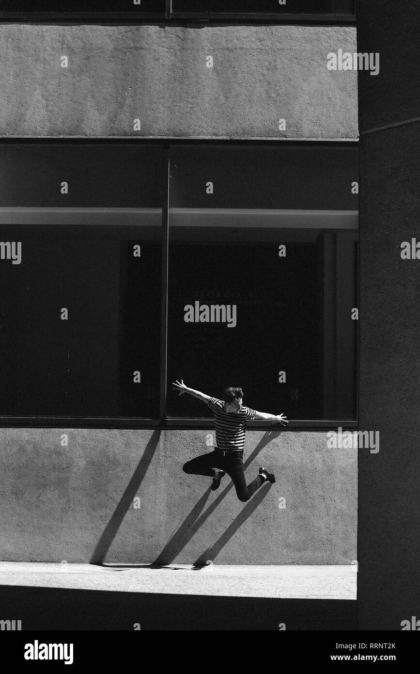 Esuberante giovane jumping contro la parete urbana Foto Stock