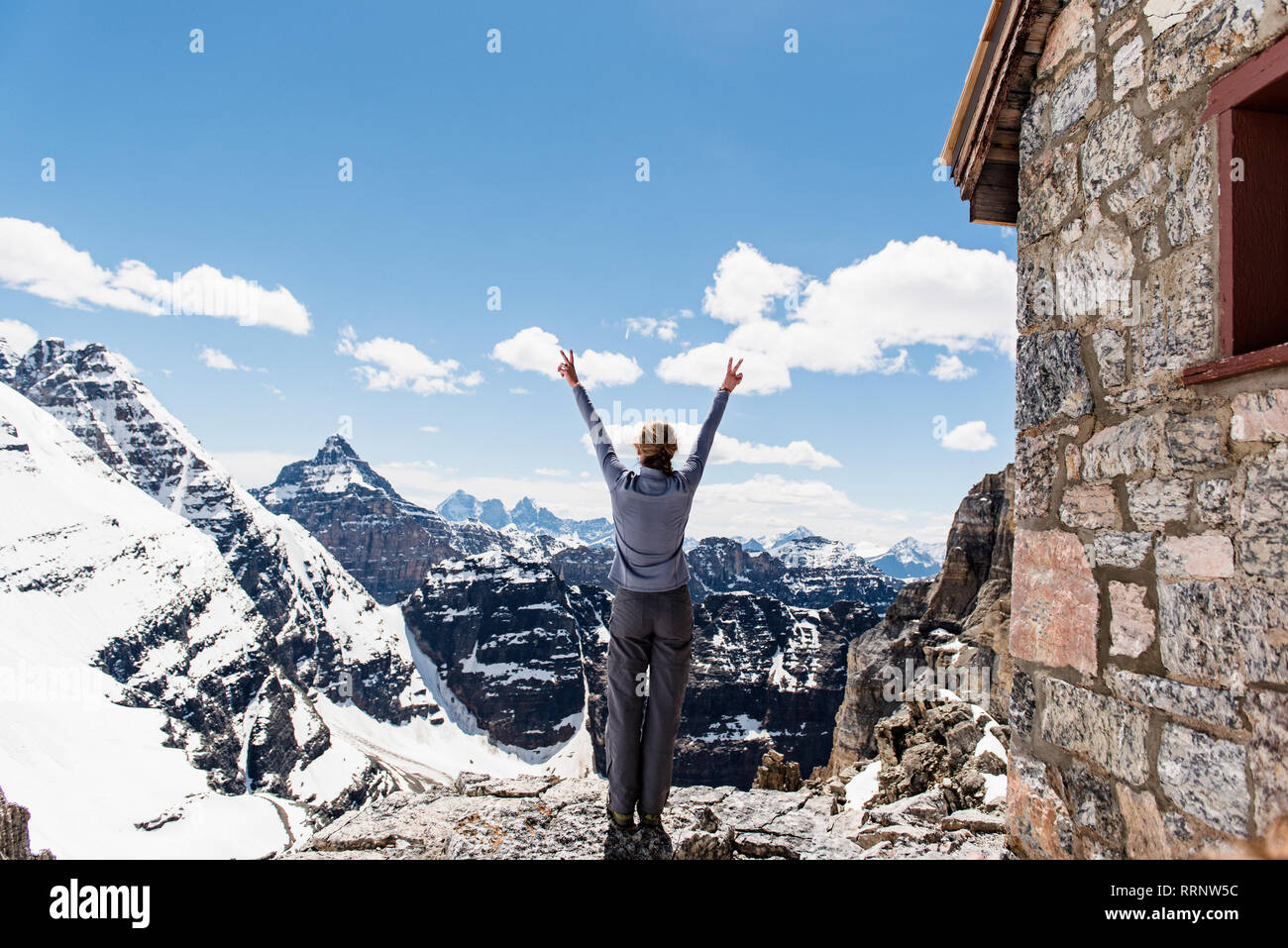 Femmina esuberante escursionista sul soleggiato, snowy cima, Yoho Park, British Columbia, Canada Foto Stock