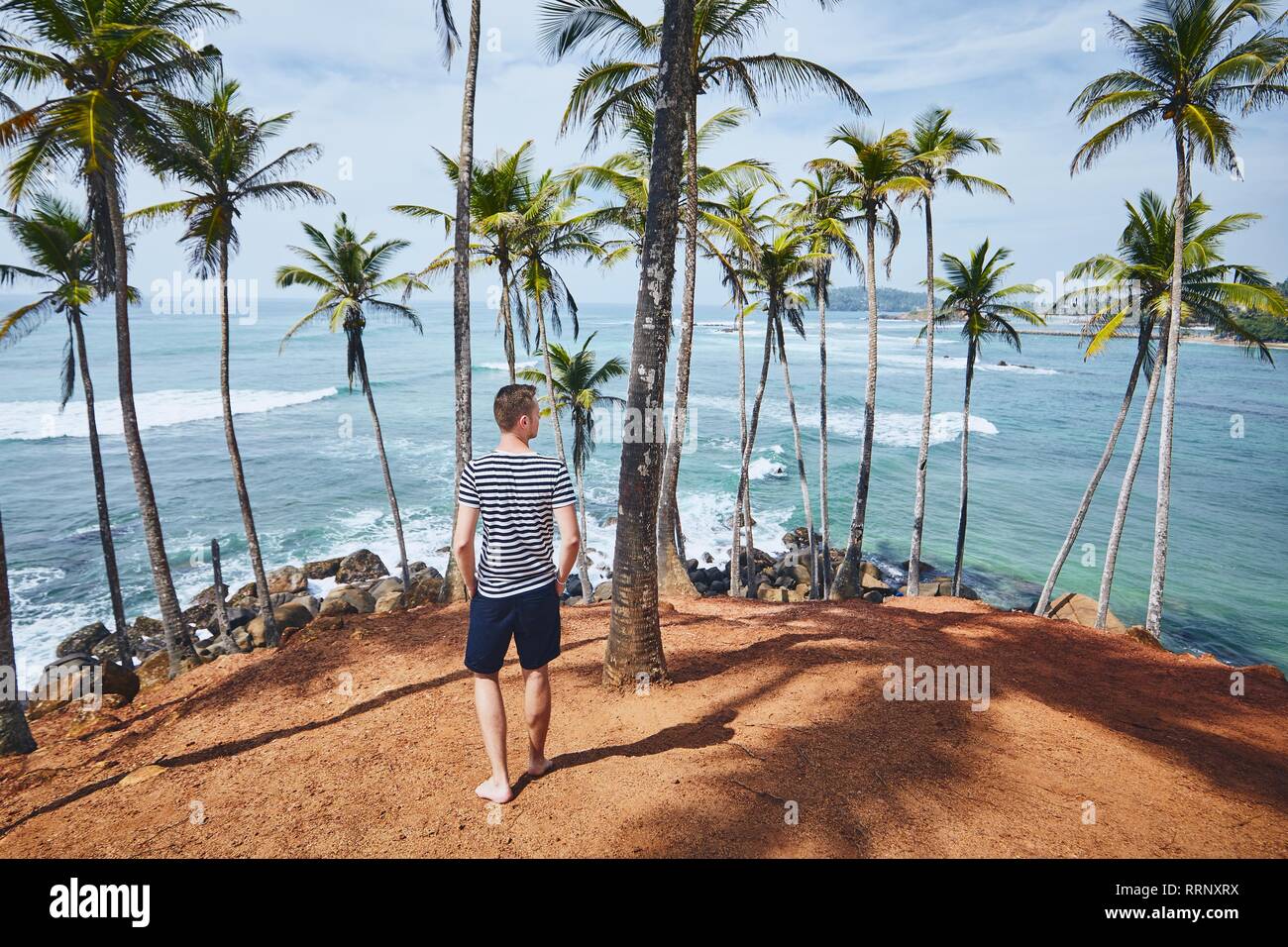 Giovane con passeggiate tra alberi di palma contro il mare. Costa in Sri Lanka. Foto Stock