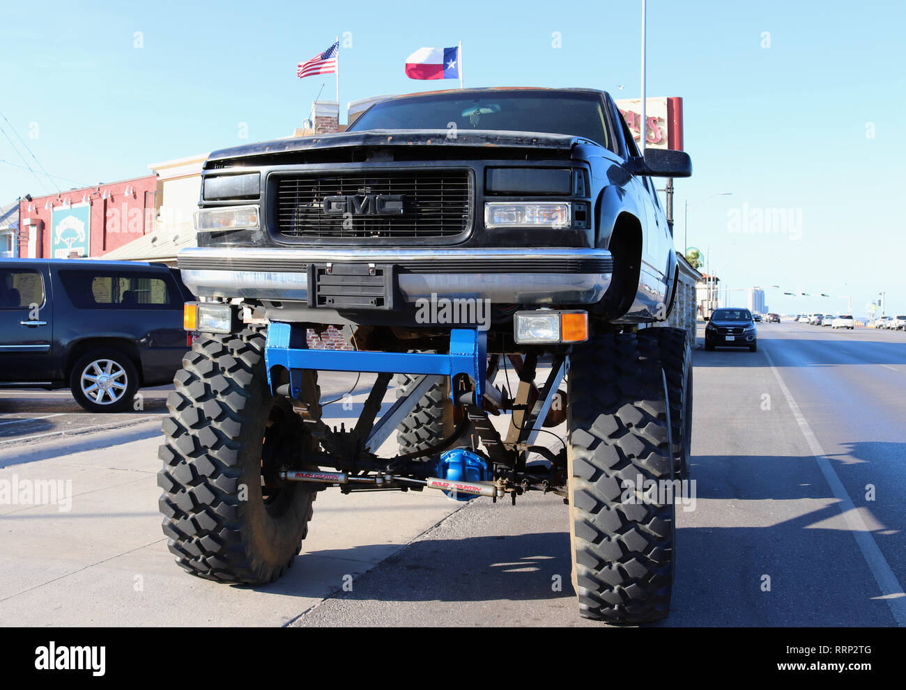 GALVESTON, Texas, Stati Uniti d'America - 9 giugno 2018: tipico texano street paesaggio. Un gigante di monster truck è parcheggiato sul boulevard. Sullo sfondo le bandiere statunitensi. Foto Stock