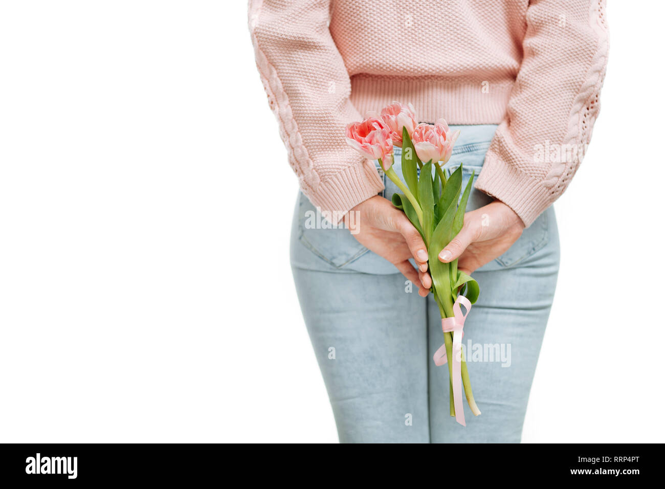 Giovane donna azienda di tulipani rosa dietro la schiena su uno sfondo bianco. Foto Stock