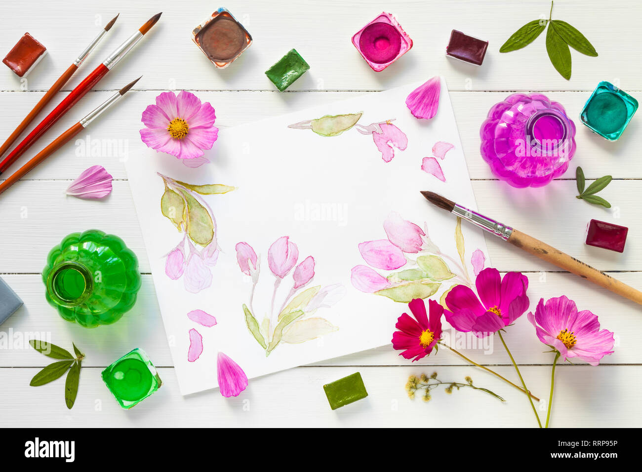 Vernici ad acquerello, pennelli per pittura, fiori di colore rosa e acquerello sketch. Vista dall'alto. Lay piatto. Foto Stock