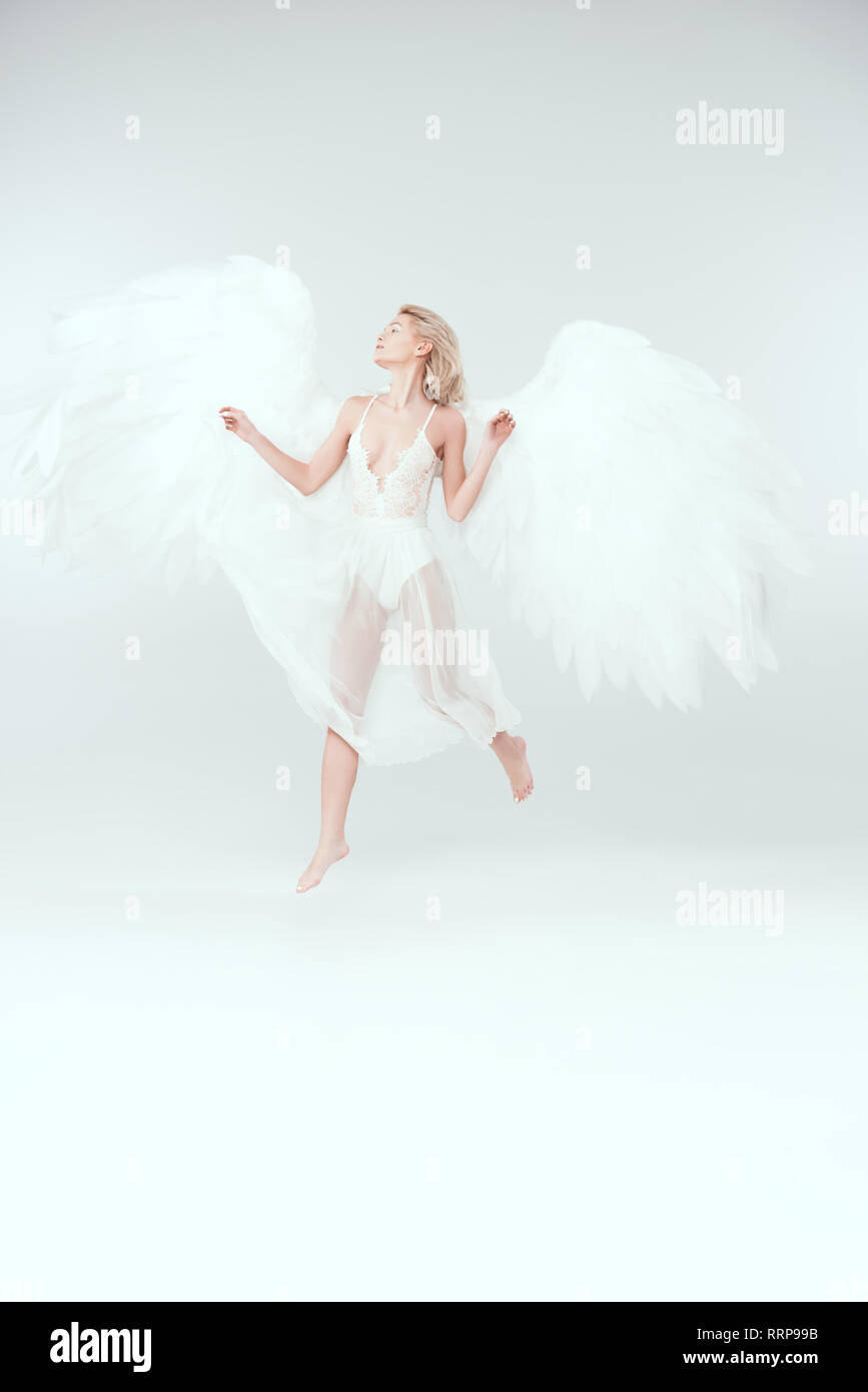 Bella donna in costume di angelo con ali jumping isolato su bianco con spazio di copia Foto Stock