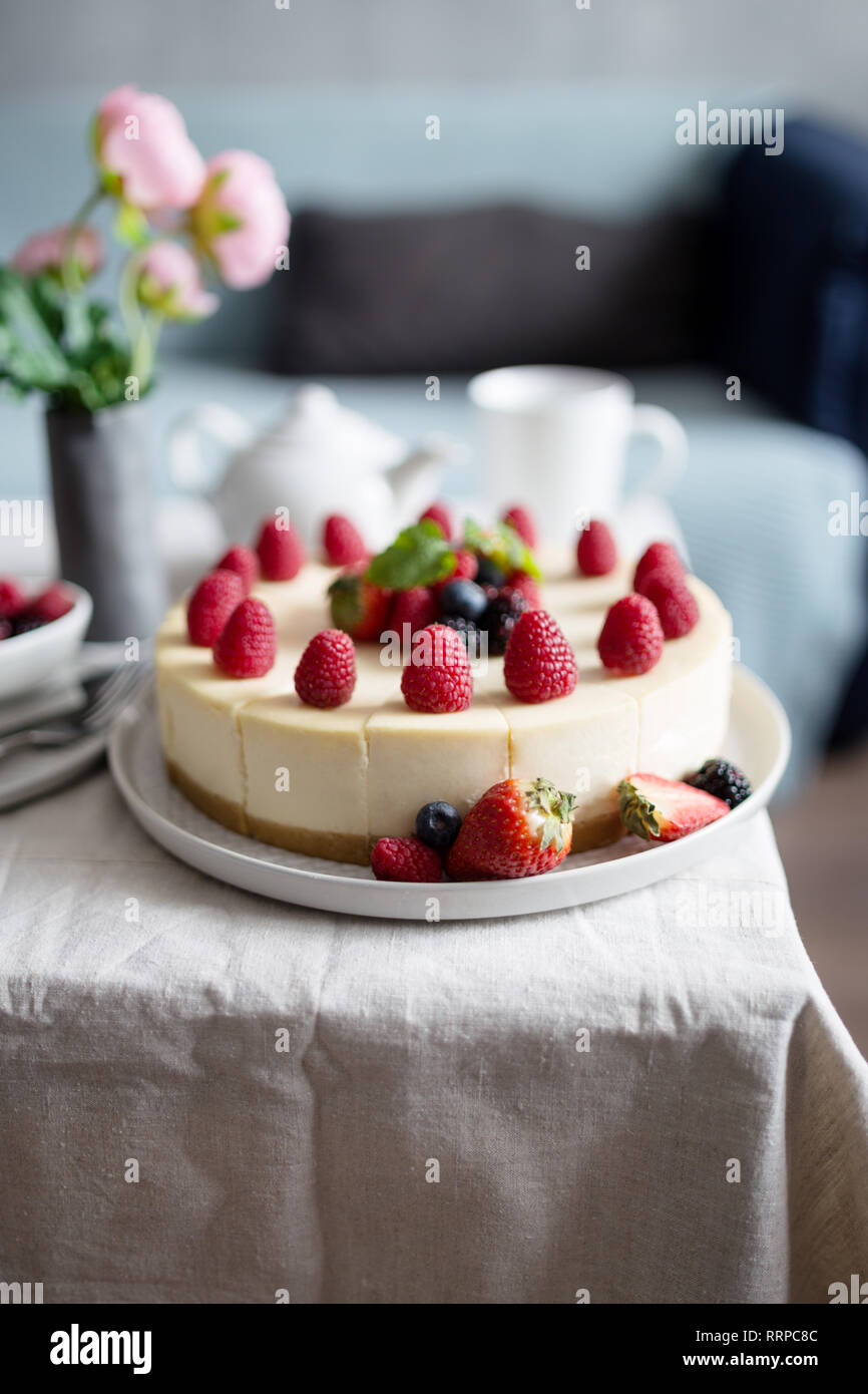 Close up cheese cake con raspberies, fragole e menta. Composizione di tea time con il dessert. Concetto di cibo dolce Foto Stock