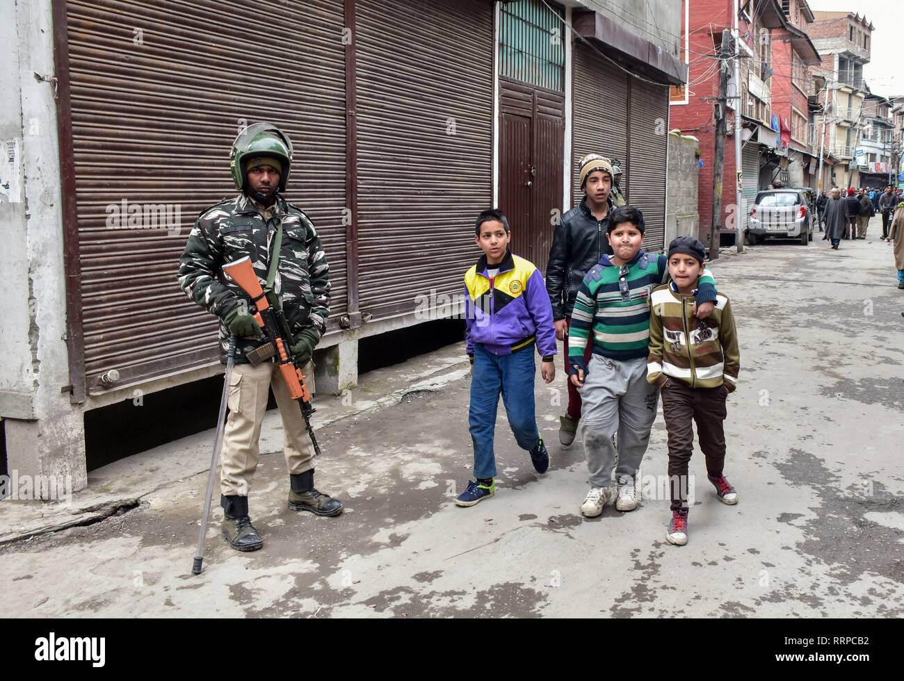 I bambini del Kashmir a piedi passato un soldato di paramilitari di allerta permanente al di fuori della casa del top leader separatista Yasin Malik, durante un raid da Indiana funzionari di intelligence in Srinagar Kashmir. La National Investigation Agency (NIA) Martedì effettuate ricerche su top leader separatista in Kashmir la valle in un terrore finanziamenti case, hanno detto i funzionari. Il NIA funzionari sono stati accompagnati dalla polizia locale e CRPF. Nel frattempo, scontri scoppiati in località Maisuma subito dopo sleuths delle indagini nazionali Agenzia effettuato incursioni su top leader separatista. Foto Stock