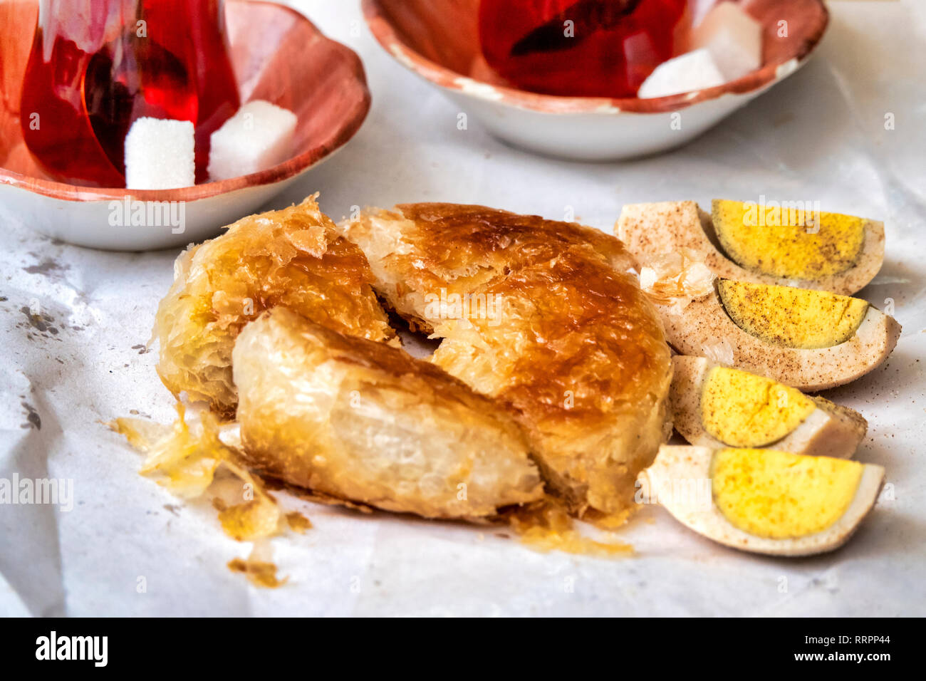 Boyoz (una pasticceria turco associato İzmir) con i tradizionali piatti di accompagnamento di tè e uova sode con pepe nero Foto Stock