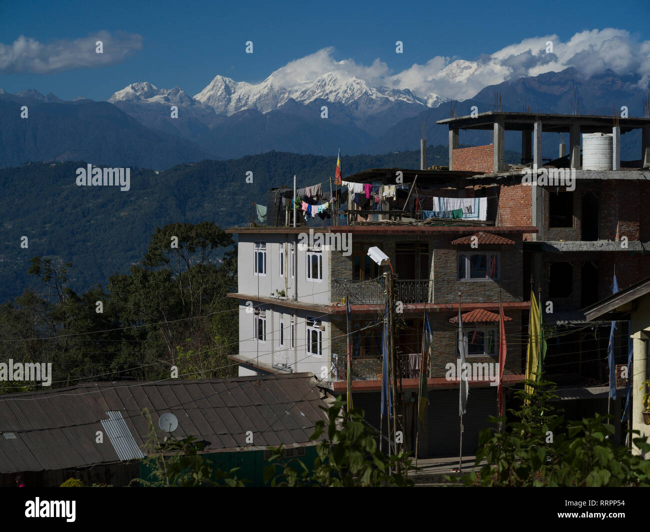 Edifici in villaggio con montagne coperte di neve in background, Kaluk, Sikkim, India Foto Stock