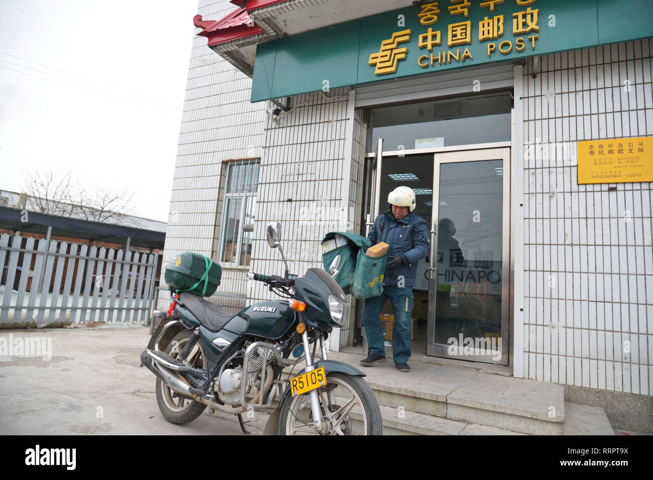 (190226) -- CHANGCHUN, Feb 26, 2019 (Xinhua) -- portalettere Jin Renzhe trasporta i pacchi postali per essere caricato sulla sua moto presso la cittadina di ramo di China Post in Chunhua township di Huichun City, a nord-est della Cina di provincia di Jilin, Feb 19, 2019. Jin Renzhe ha lavorato come un postino per 30 anni in Chunhua Township, dove il servizio postale è inadeguata a causa dei ripidi sentieri di montagna e liberamente i villaggi sparsi. Nonostante che, Jin riesce a consegnare la posta per gli abitanti di un villaggio lo stesso giorno e-mail arrivano nella città. Come molti giovani lavorano al di fuori della città, Jin ponti a loro e ai loro genitori attraverso Foto Stock
