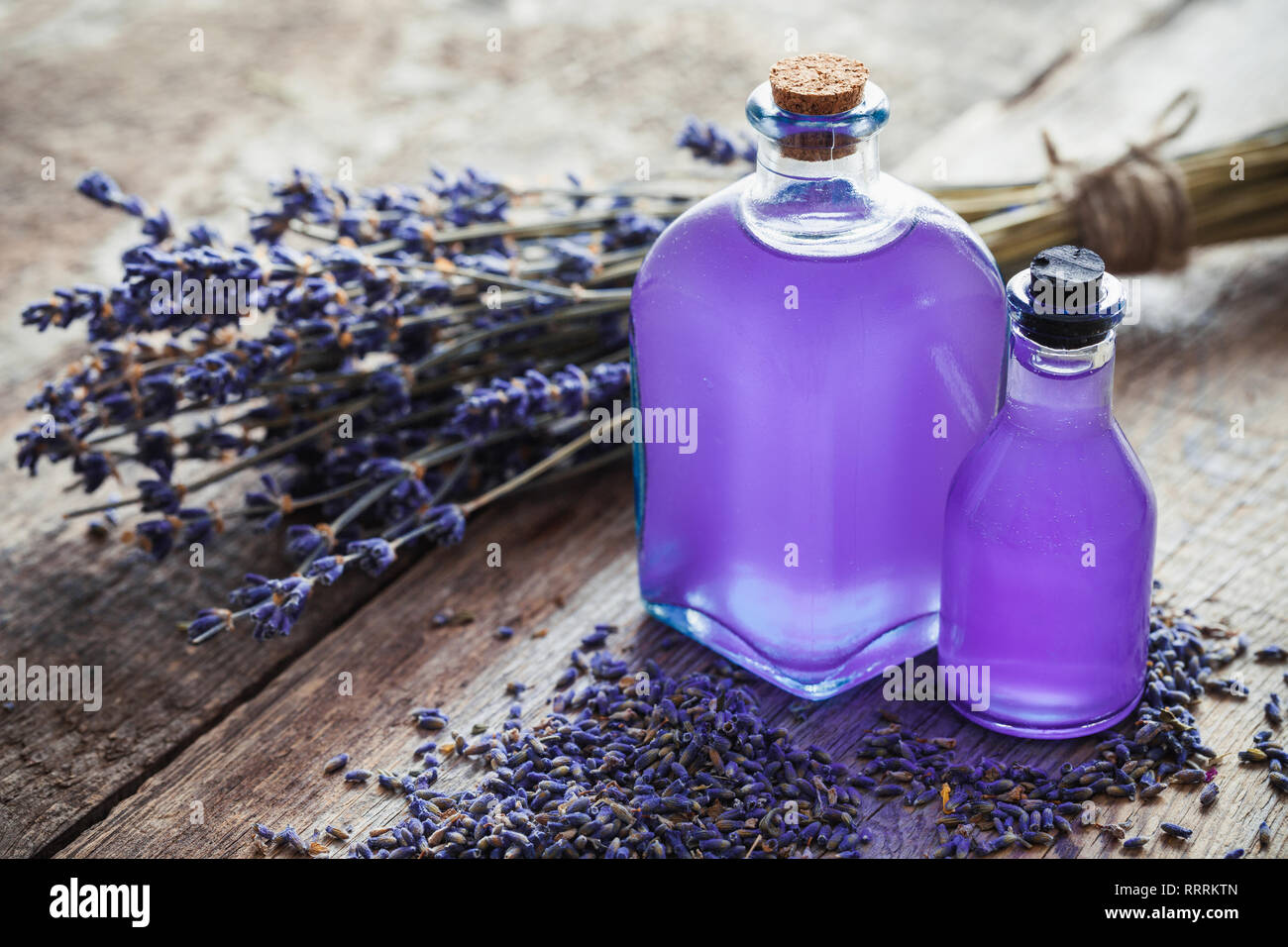 Bottiglie di olio essenziale di lavanda e mazzo di fiori e sul tavolo. Retrò tonica. Messa a fuoco selettiva. Foto Stock