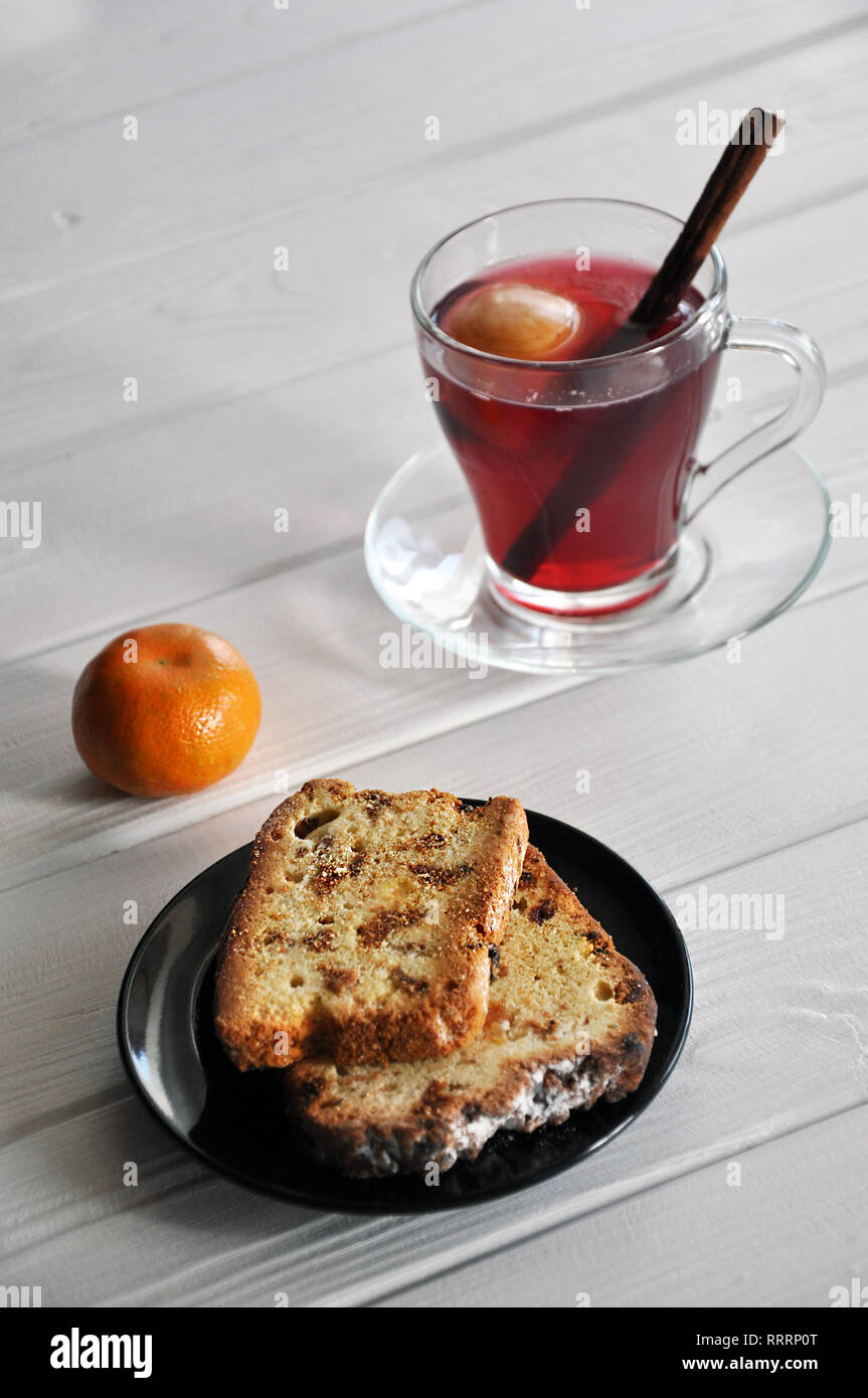 Fette di pane dolce con uvetta sulla piastra nera, servita con mandarin e apple-dewberry composta con la stecca di cannella sul bianco tavolo in legno, Foto Stock