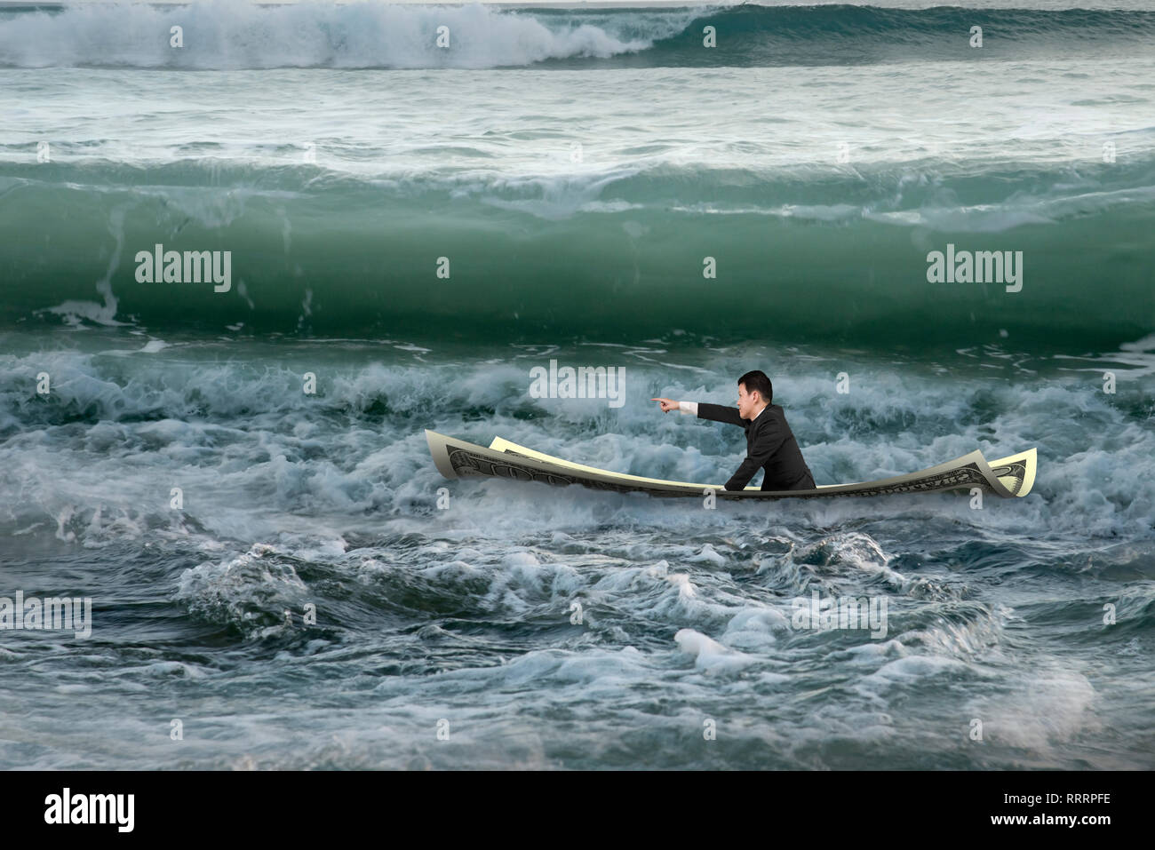 Imprenditore con un dito puntato gesto seduto sulla barca di denaro nell'oceano con onde che sopraggiungono Foto Stock