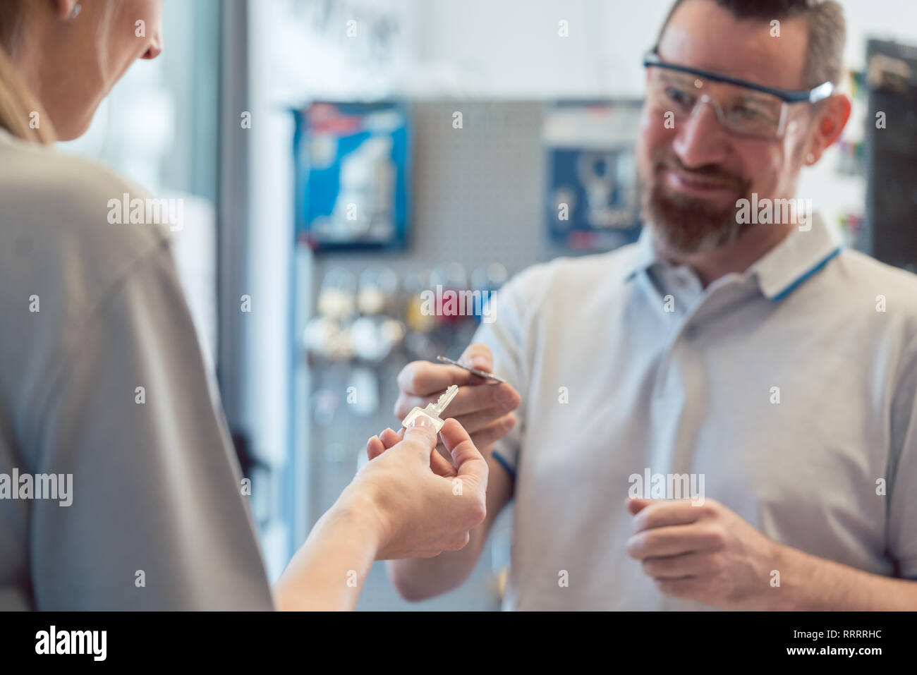 Donna di conversazione con il cliente a keymaker o fabbro Foto Stock