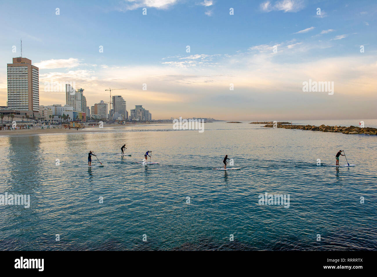 Un gruppo di stand up paddle boarders praticando la mattina presto spento la spiaggia urbana di Tel Aviv, Israele Foto Stock