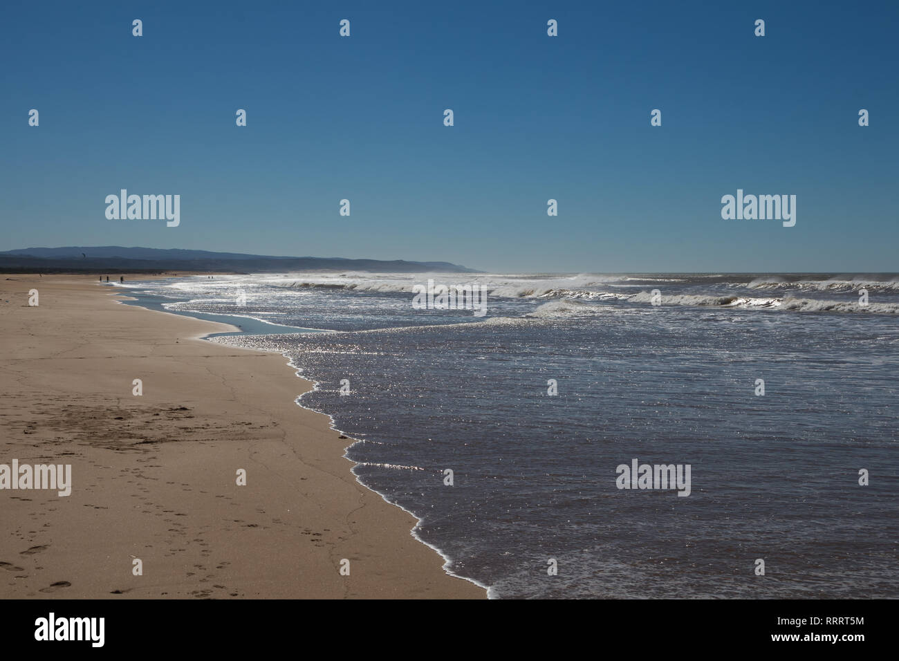 Calma autunno wellknown surfers beach. Giallo sabbia e oceano Atlantico con onde. Montagna in background. Azzurro cielo. Sidi Kaouki, Marocco. Foto Stock