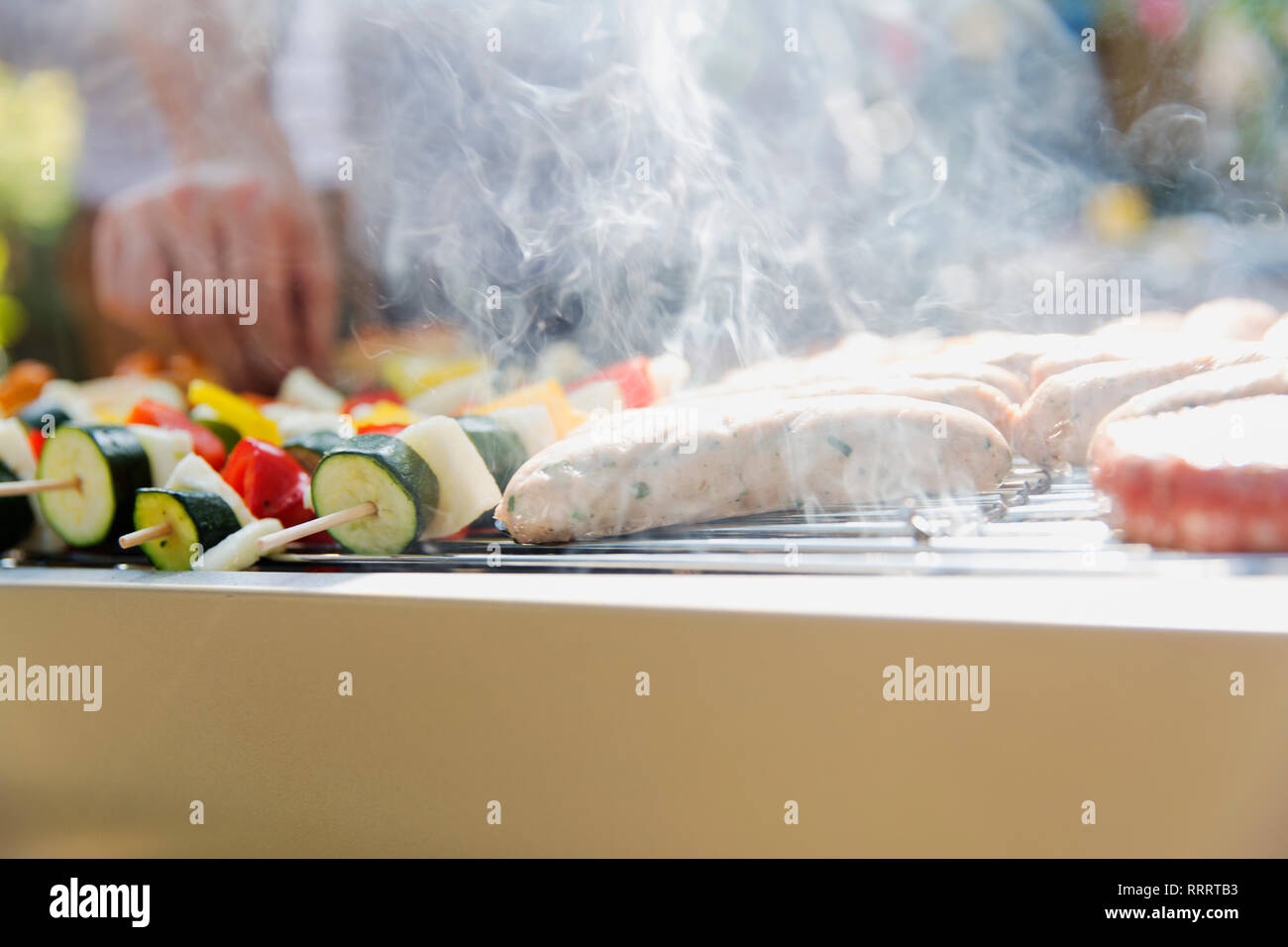 Close up salsicce e spiedini di verdure per la cottura, cottura a vapore sul barbecue grill Foto Stock