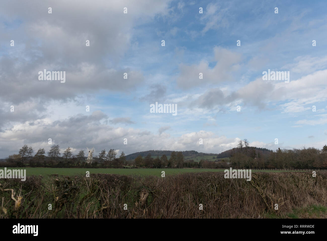 Immagine del paesaggio di campagna con le nuvole e il mulino a vento impostato nel Regno Unito Galles Foto Stock