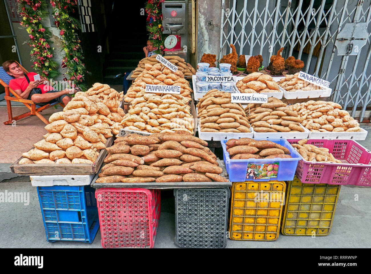 Manila, Filippine - 12 Febbraio 2017: una varietà di Taiwan di patate dolci in cesti per la vendita in un Street a Chinatown con un fornitore maschio Foto Stock