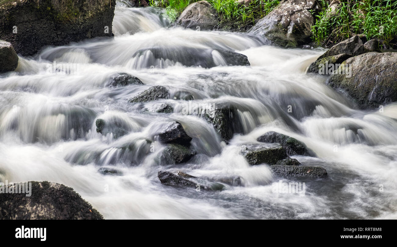 Bella la rapida che scorre veloce con acqua e rocce, lunga esposizione. Naturale corsa stagionale all'aperto in background della Finlandia Foto Stock