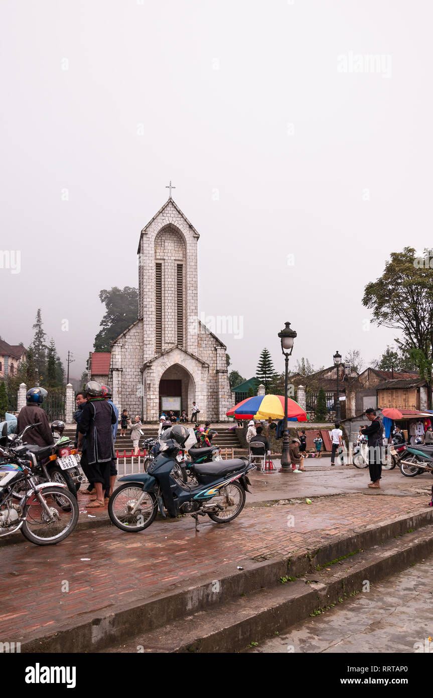 Nhà Thờ Đá Sapa o la cattedrale di Notre Dame con vietnamita locale al di fuori su di un giorno nuvoloso, Sa Pa, Vietnam Foto Stock