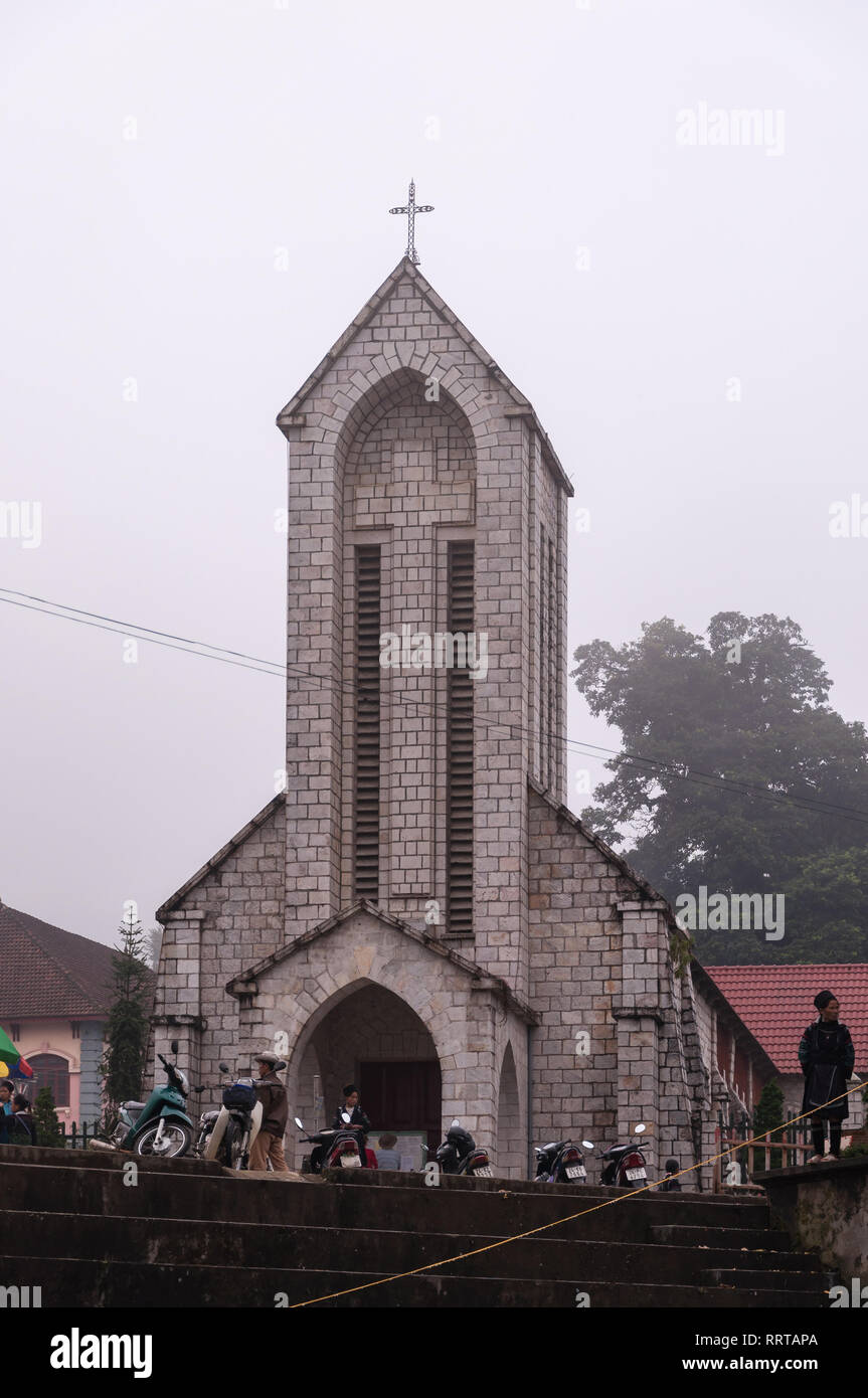 Nhà Thờ Đá Sapa o la cattedrale di Notre Dame con vietnamita locale al di fuori su di un giorno nuvoloso, Sa Pa, Vietnam Foto Stock