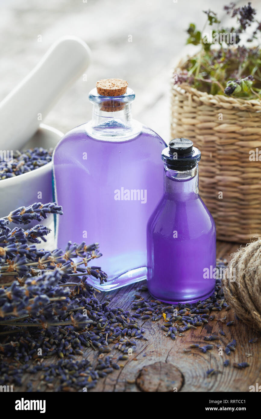Bottiglie di olio essenziale, malta e Lavanda fiori mazzetto sul tavolo. Retrò tonica. Messa a fuoco selettiva. Foto Stock