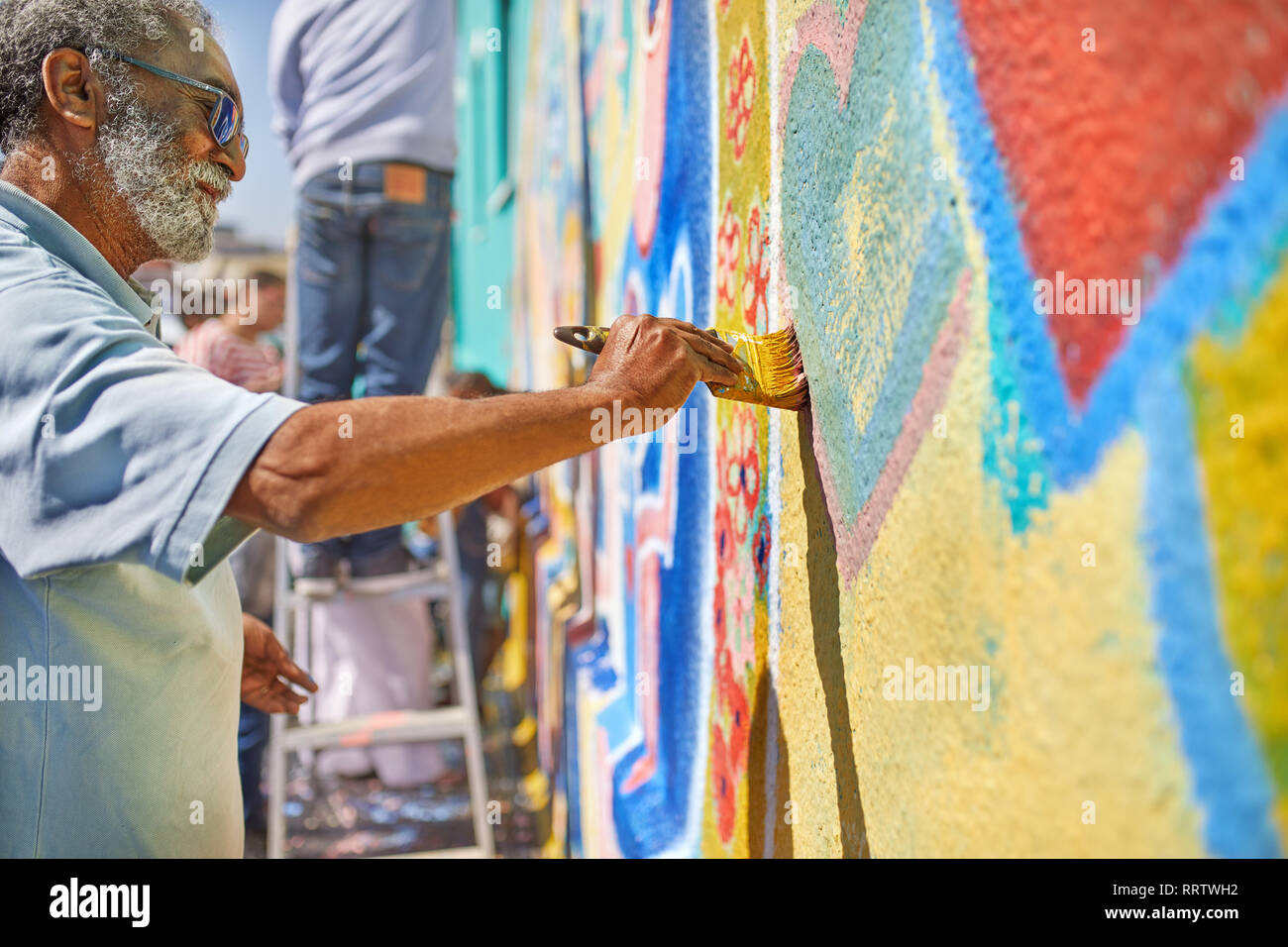 Senior uomo pittura murale sulla parete soleggiato Foto Stock