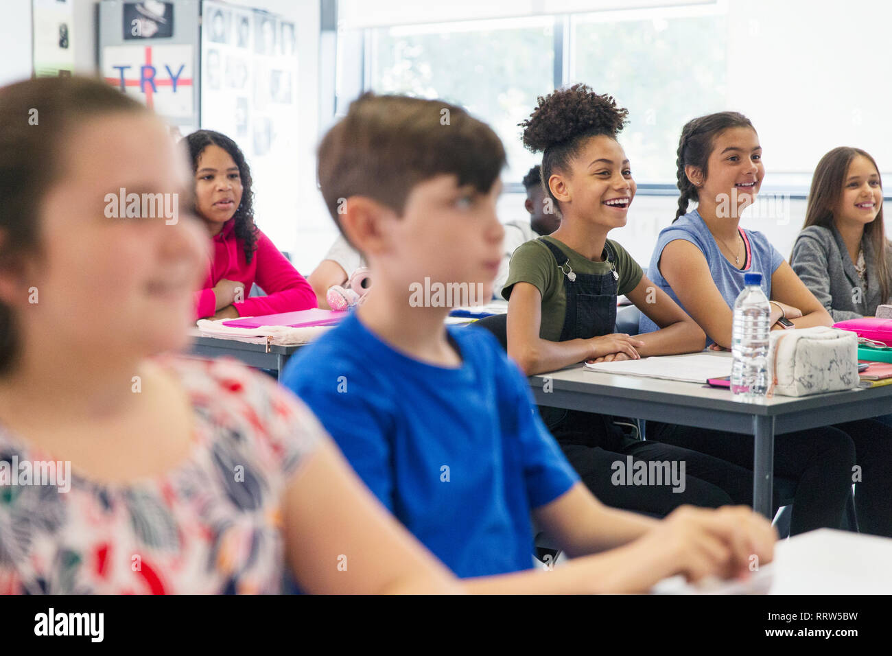 Sorridente junior high school di ascolto gli studenti nella lezione in aula Foto Stock