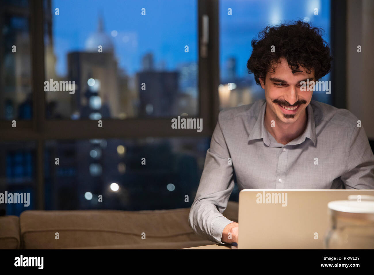 Uomo con notebook in ambiente urbano appartamento a notte Foto Stock