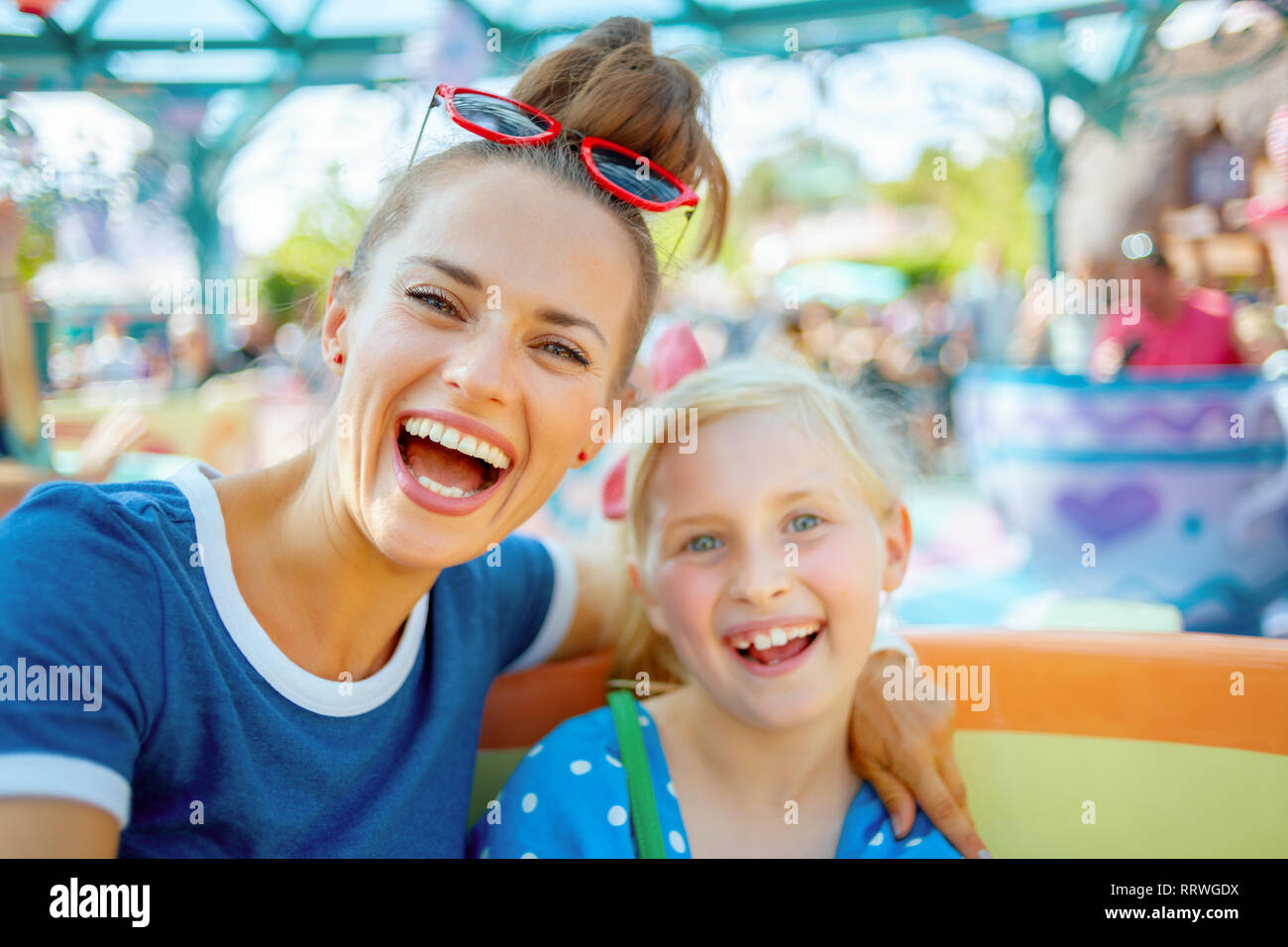 Ritratto di moderna sorridente madre e bambino di turisti nel parco a tema godendo di attrazione. Foto Stock