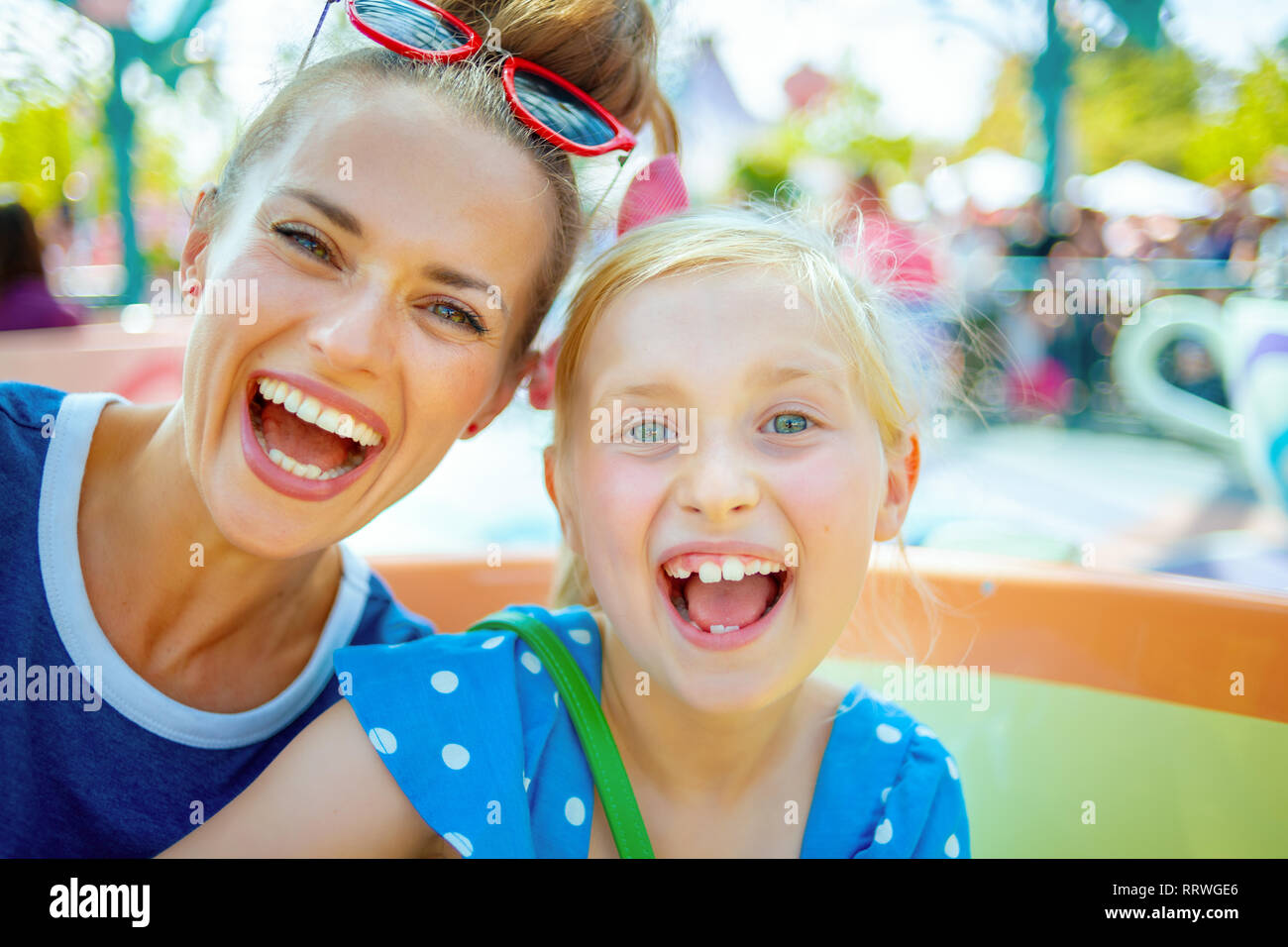 Ritratto di giovane sorridente madre e bambino di turisti nel parco a tema avente corsa. Foto Stock