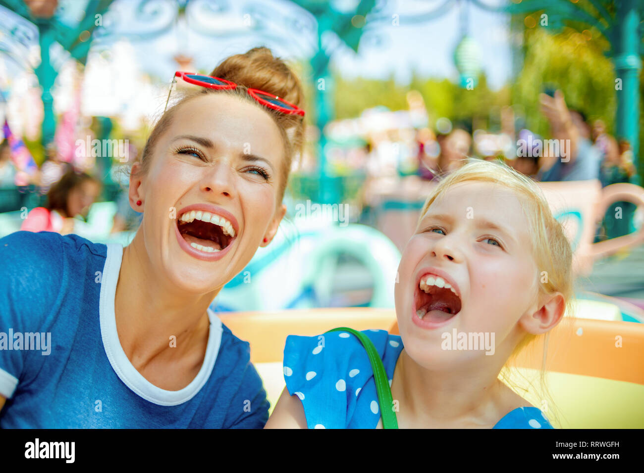 Moderno sorridente madre e bambino di viaggiatori nel parco divertimenti godendo di corsa. Foto Stock