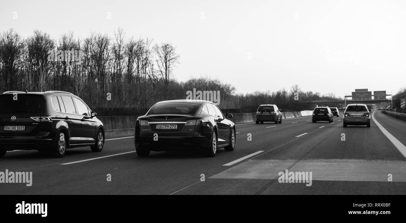 Germania - Feb 25, 2018: Lusso Tesla P85 e più auto guida su la sera d'inverno sull'autostrada tedesca con la direzione Offenburg, Basilea, Frankfurt monocromatico Foto Stock
