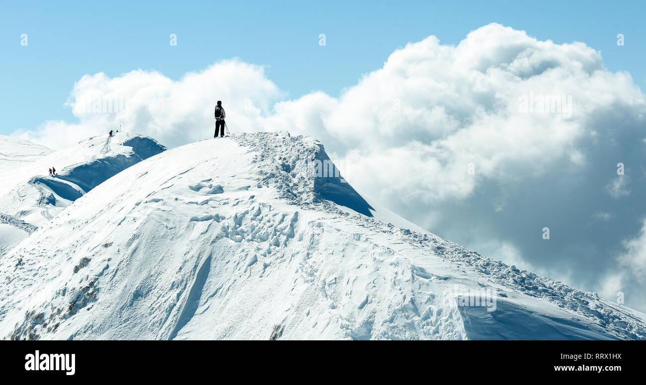 Persona escursionismo su un cornicione di montagna azienda bastoncini da sci Foto Stock