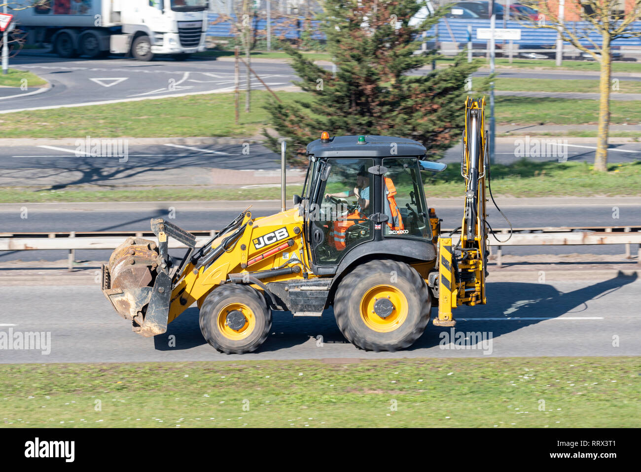 JCB escavatore digger trasportare attrezzature supplementari la guida su strade pubbliche, su strada. Il caricatore retroescavatore, chiamato anche un caricatore retroescavatore, SCAVATRICE Foto Stock