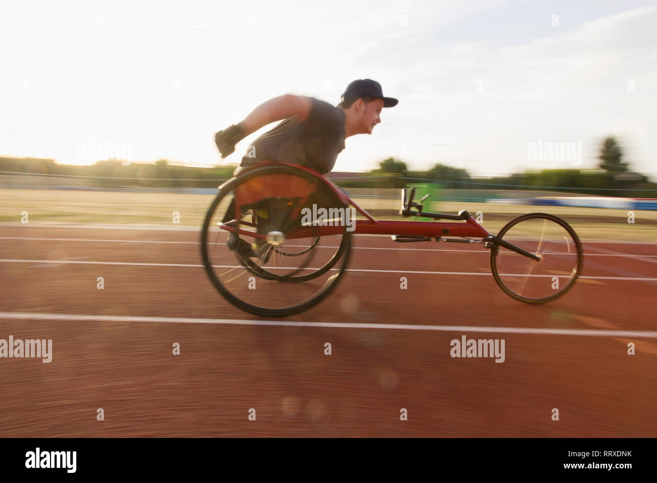 Ragazzo adolescente atleta paraplegico accelerando lungo la via dello sport in carrozzella gara Foto Stock