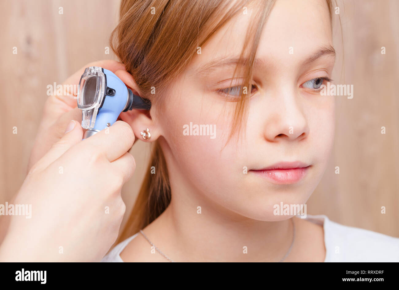Femmina esamina pediatra elementari di età ragazza l orecchio in clinica pediatrica. Medico utilizzando un otoscopio o auriscope per controllare il canale uditivo e timpano membra Foto Stock