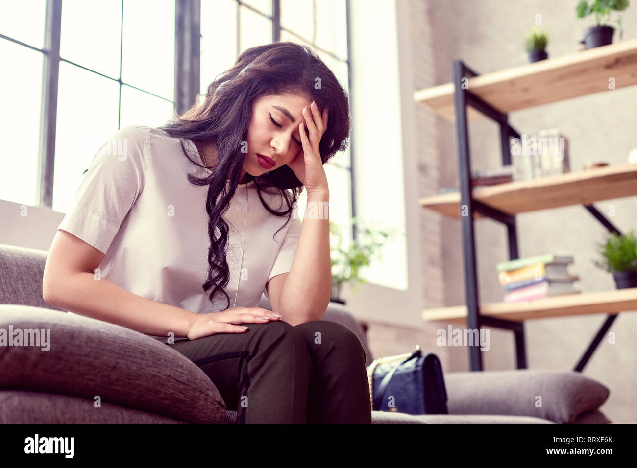 Cupa stanco giovane donna tenendo la fronte Foto Stock