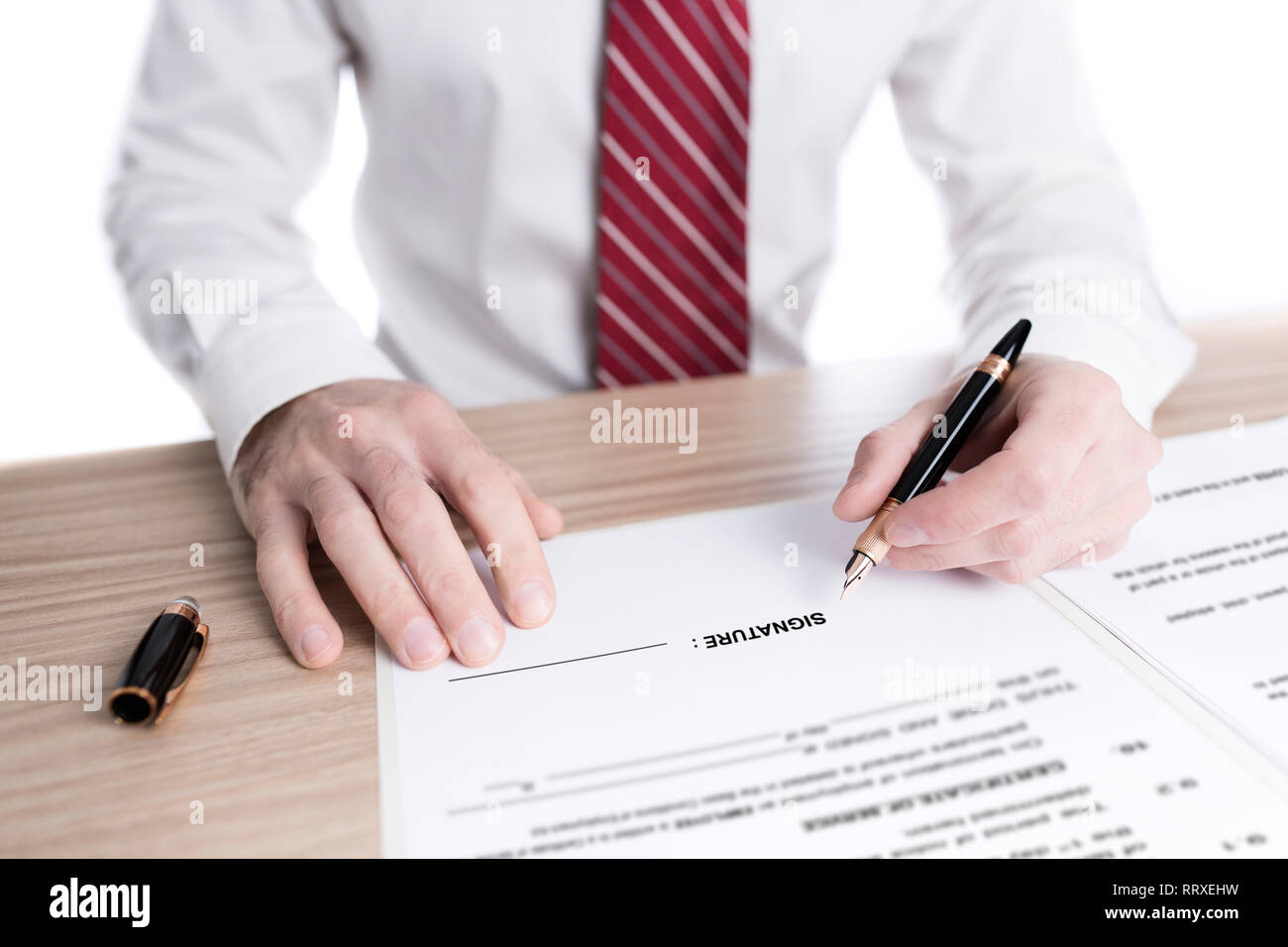 Imprenditore in camicia e cravatta firma un contratto di carta con una penna stilografica su una scrivania Foto Stock