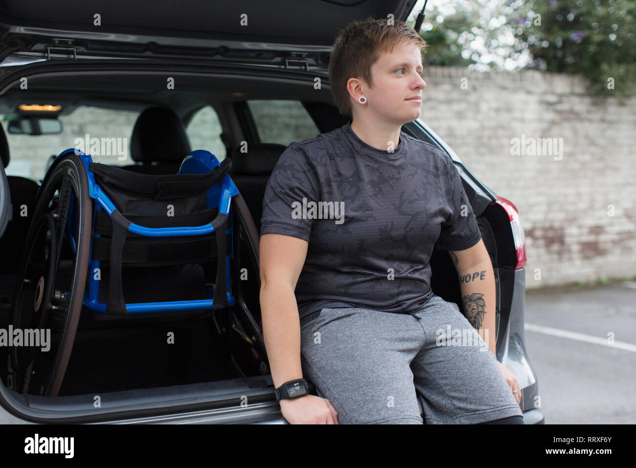 Fiducioso giovane donna con sedia a rotelle sul retro della macchina Foto Stock