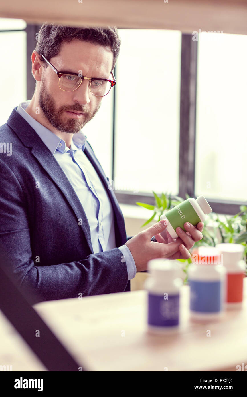 Bello smart imprenditore tenendo una bottiglia con le pillole Foto Stock