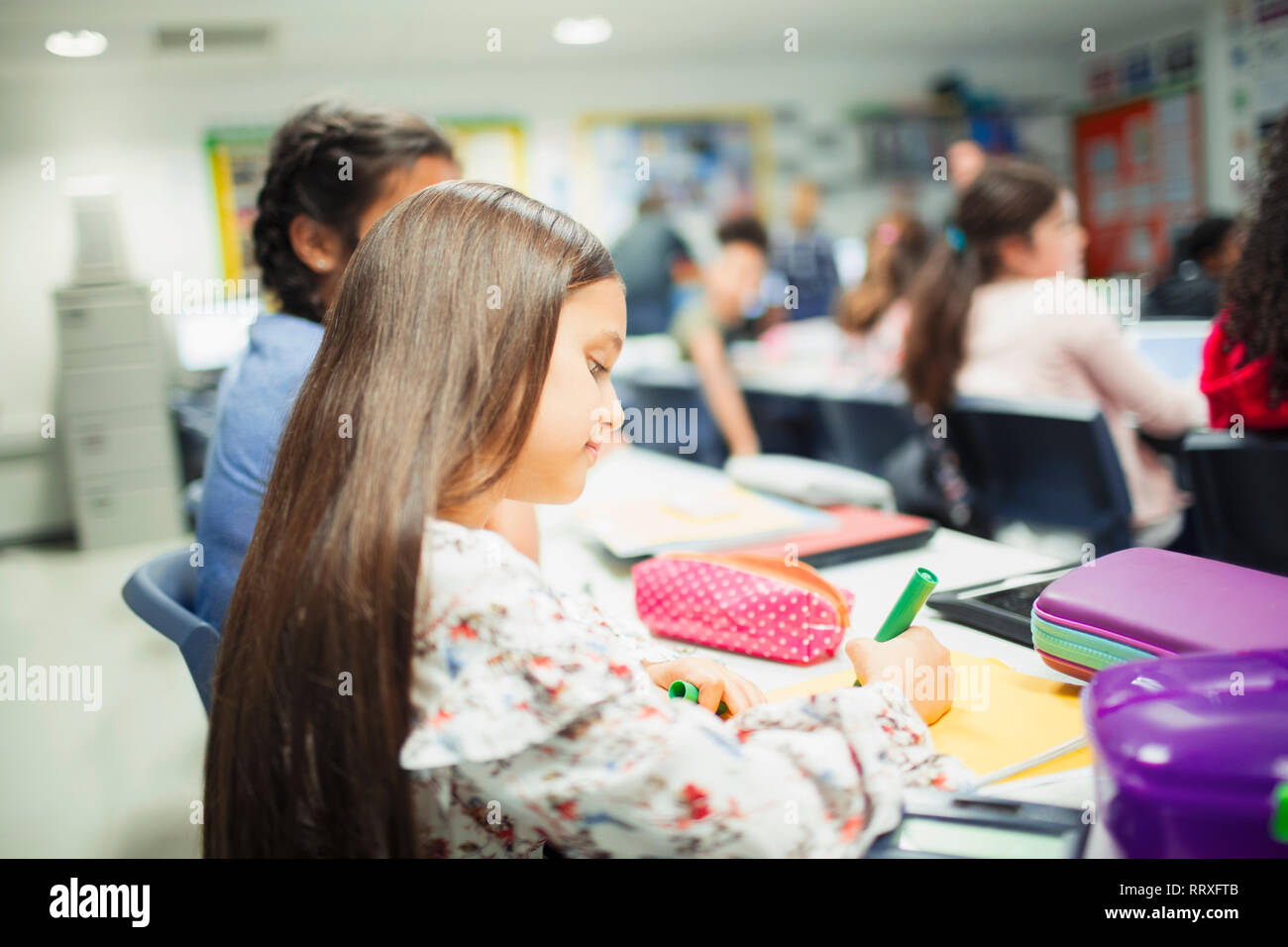 Junior high school girl studente facendo i compiti al banco in aula Foto Stock