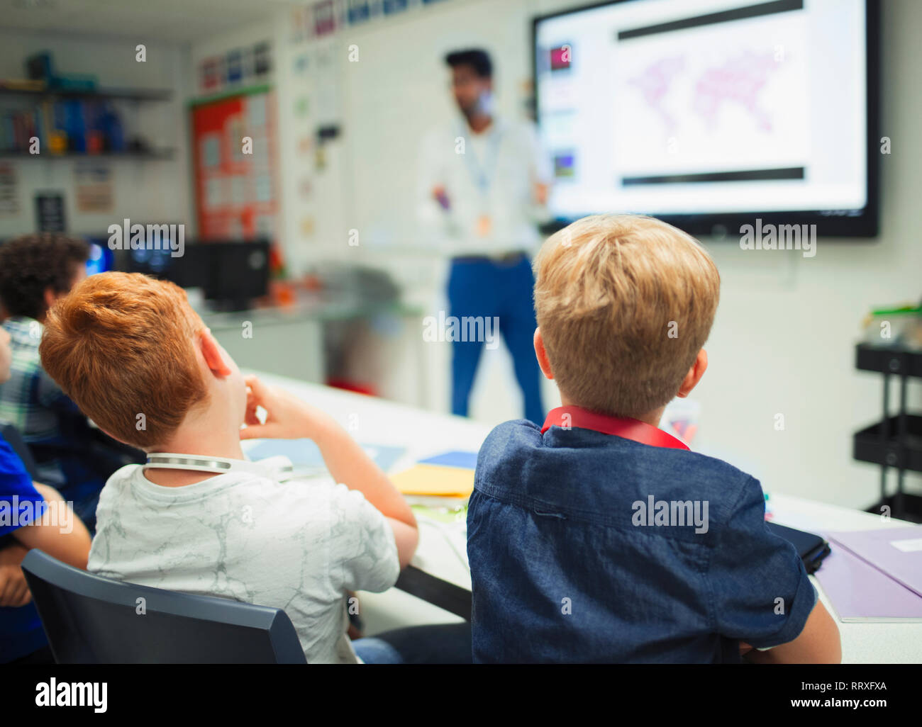 Junior high school boys guardando insegnante durante la lezione in aula Foto Stock