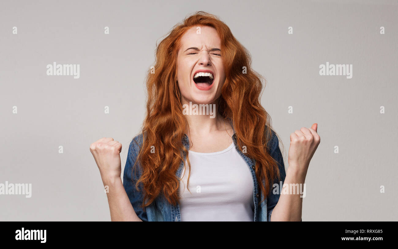 Overjoyed giovani redhead donna urla di gioia Foto Stock