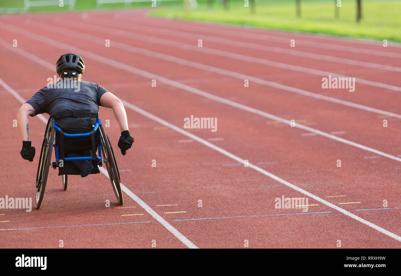 Femmina atleta paraplegico accelerando lungo la via dello sport in carrozzella gara Foto Stock