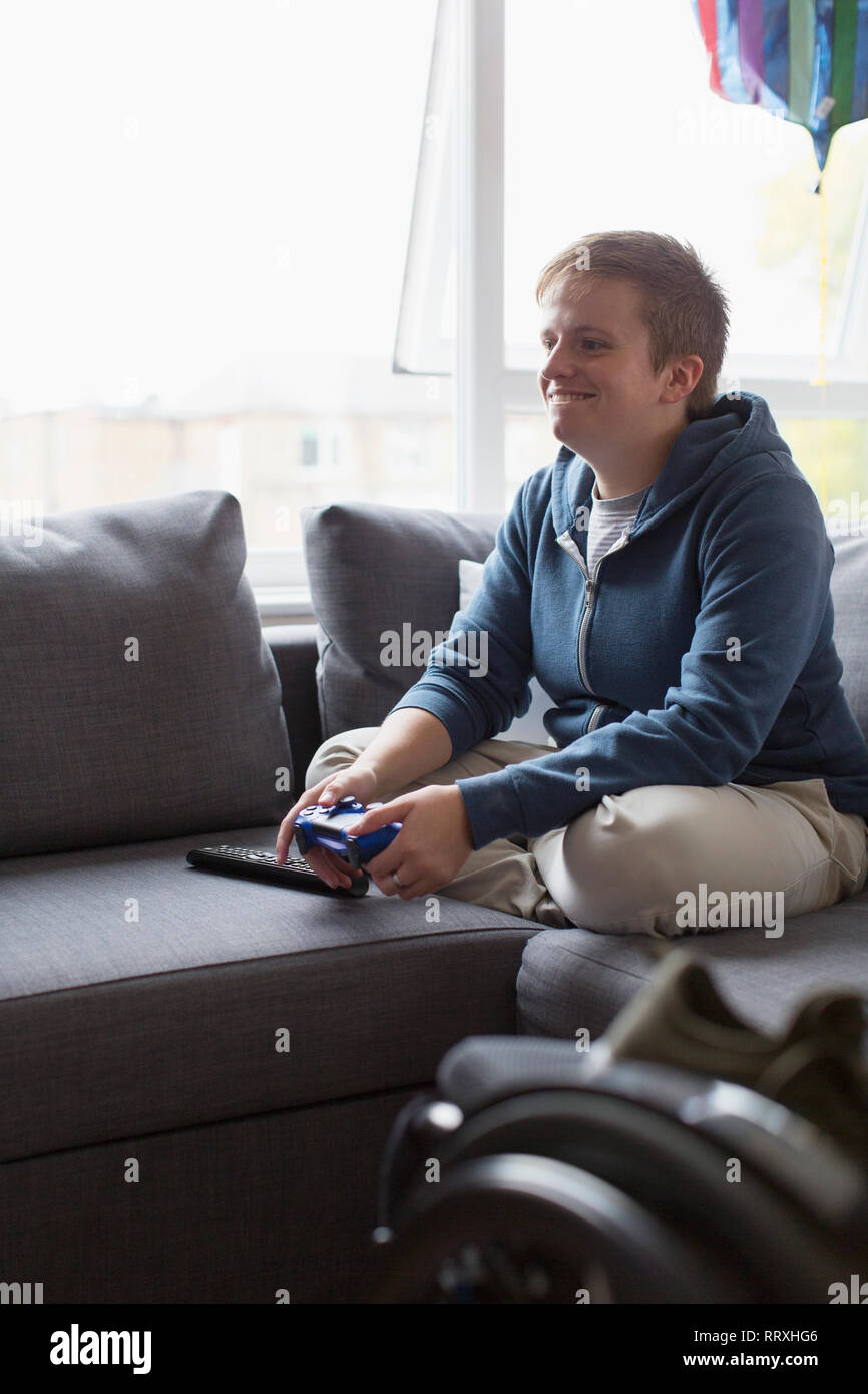 Sorridente giovane donna la riproduzione del video gioco sul divano Foto Stock