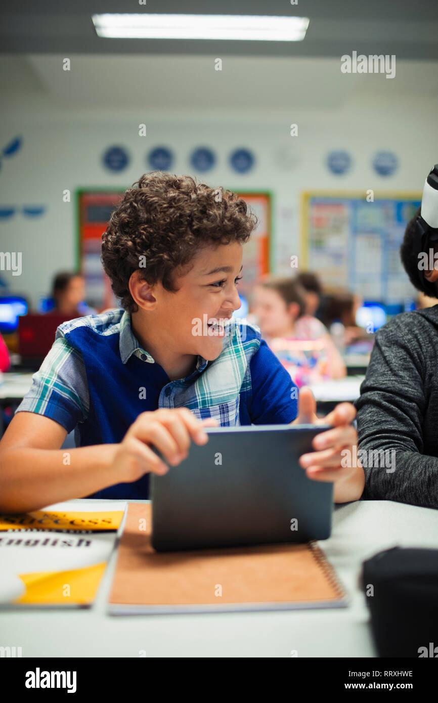 Felice scuola elementare boy utilizzando digitale compressa in aula Foto Stock