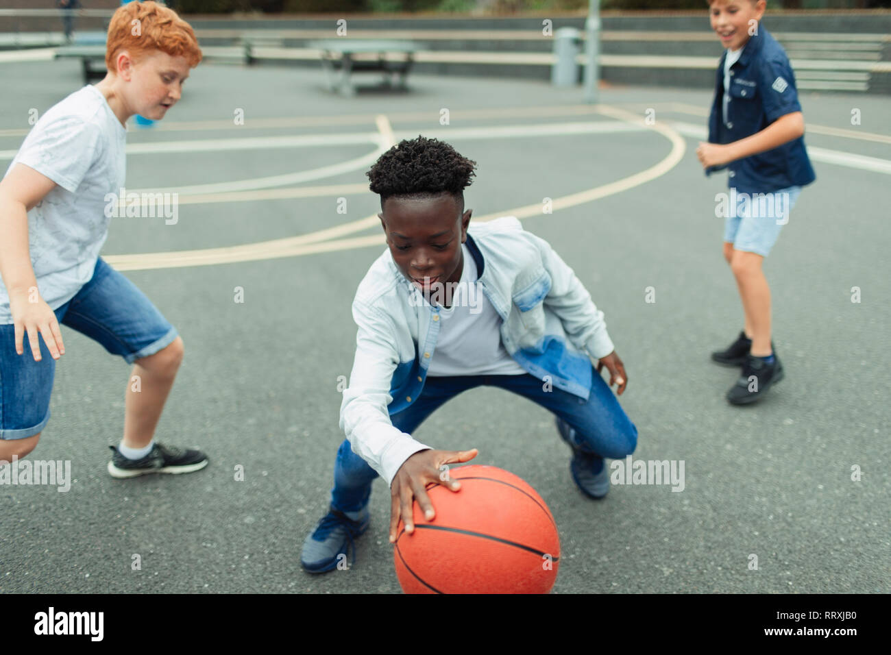 Tween ragazzi giocare a basket in schoolyard Foto Stock